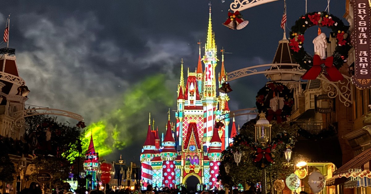 Cinderella Castle with holiday projections and fireworks smoke, seen from Main Street at the Christmas party