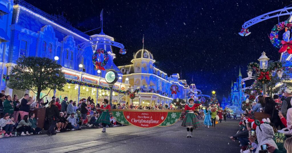 Dancers carrying the Mickey's Once Upon a Christmastime Parade banner down Main Street at the Christmas party